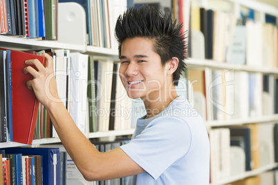 University student selecting book from library shelf