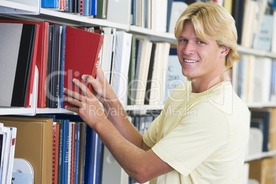 University student selecting book from library