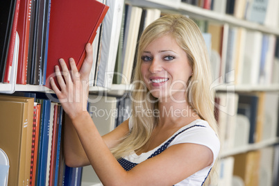 University student selecting book from library