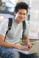 Male student using laptop outside
