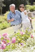 Grandfather and grandson outdoors in garden pointing at plants a