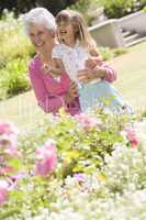 Grandmother and granddaughter outdoors in garden smiling
