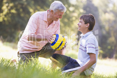 Grandfather and grandson at a park with a ball smiling