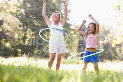 Grandmother and granddaughter at a park hula hooping and smiling