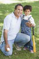 Grandfather and grandson holding baseball bat and smiling