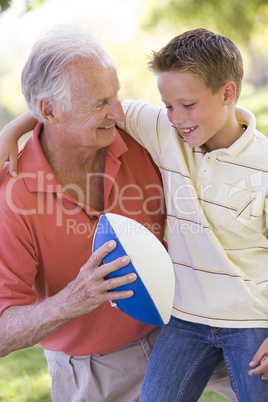 Grandfather and grandson outdoors with football smiling