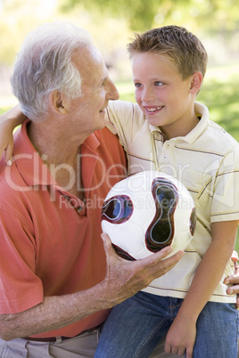 Grandfather and grandson outdoors with ball smiling