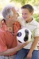 Grandfather and grandson outdoors with ball smiling