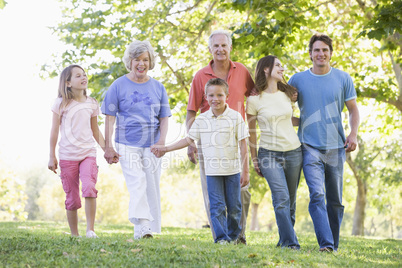 Extended family walking in park holding hands and smiling Extended family walking in park holding hands and smiling