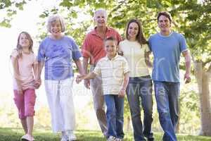 Extended family walking in park holding hands and smiling