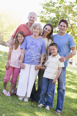 Extended family standing in park holding hands and smiling