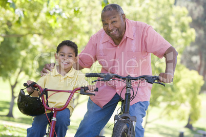 Grandfather and grandson on bikes outdoors smiling