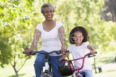 Grandmother and granddaughter on bikes outdoors smiling