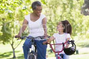 Grandmother and granddaughter on bikes outdoors smiling