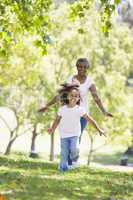 Grandmother and granddaughter running in park and smiling