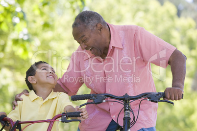 Grandfather and grandson on bikes outdoors smiling