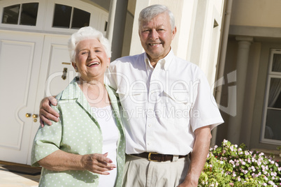 Senior couple standing outside house