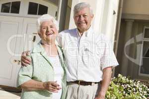 Senior couple standing outside house