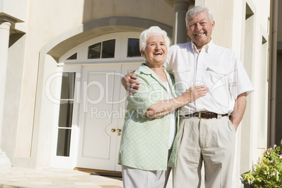 Senior couple standing outside house