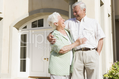 Senior couple standing outside house