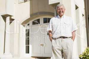 Senior man standing outside house