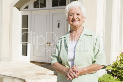 Senior woman standing outside house