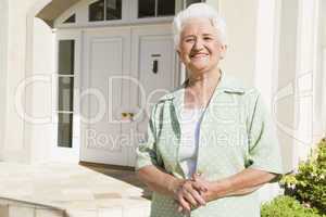 Senior woman standing outside house
