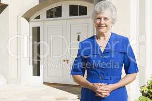 Retired woman standing outside house