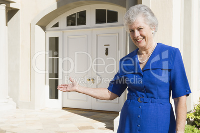 Senior woman standing outside home