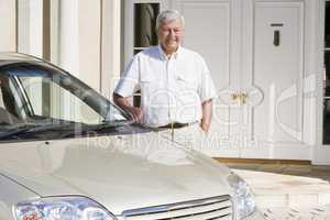 Senior man standing next to new car