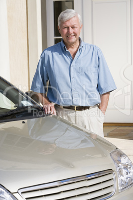 Senior man standing next to new car