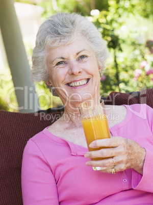 Eine altere Frau drinkt ein Glas Saft