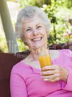 Eine altere Frau drinkt ein Glas Saft