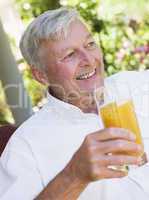 Eine älterer Mann drinkt ein Glas Saft