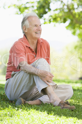 Eine älterer Mann sitzt auf einer Wiese