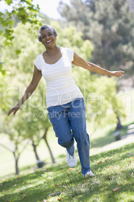 Eine ältere dunkelhäutige Frau läuft glücklich über eine Wiese