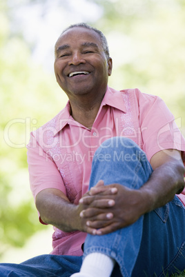 Ein älterer dunkelhäutiger Mann sitzt auf einer Wiese