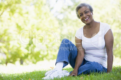 Eine ältere dunkelhäutige Frau sitzt auf einer Wiese