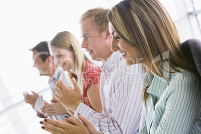 Four businesspeople applauding indoors smiling