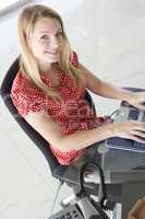 Businesswoman sitting in office typing on laptop smiling