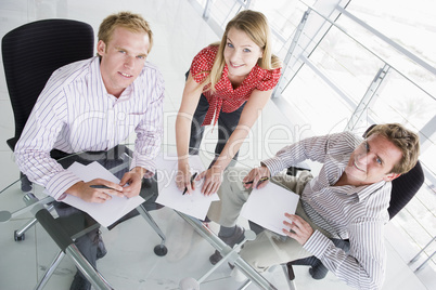 Three businesspeople in a boardroom with paperwork smiling