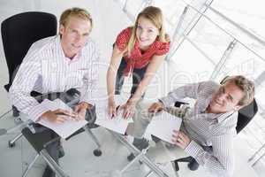 Three businesspeople in a boardroom with paperwork smiling