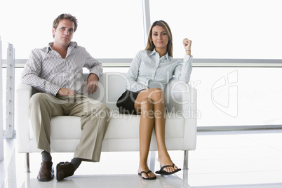 Two businesspeople sitting in office lobby smiling