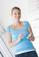 Woman standing in corridor using personal digital assistant smil