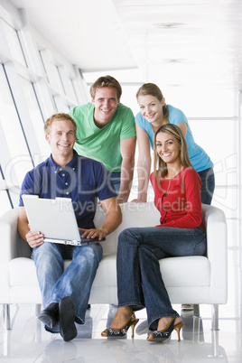 Four people in lobby with laptop smiling
