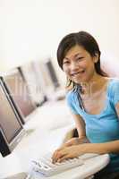 Woman sitting in computer room typing and smiling