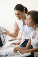 Two women in computer room where one is assisting the other