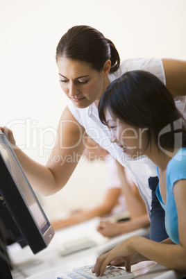Two women in computer room where one is assisting the other