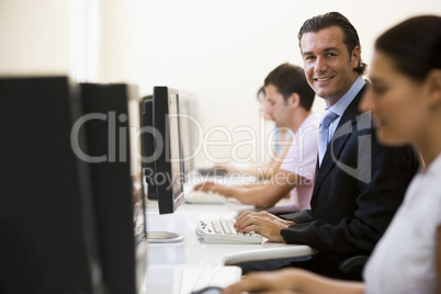 Four people in computer room with one man wearing a suit smiling