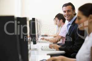 Four people in computer room with one man wearing a suit smiling